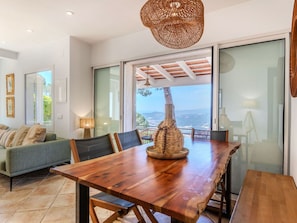 A dining area with a wooden table, chairs, and a woven light fixture.