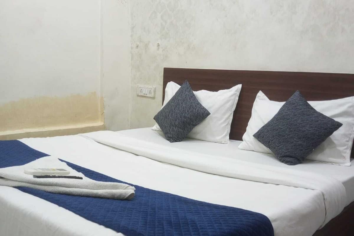A neatly made bed with white and blue bedding, two pillows, and a folded towel.