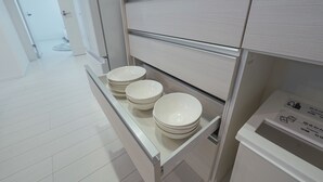 Een moderne keuken met witte kasten, een inbouwvaatwasser en een aanrecht met gestapelde witte borden.