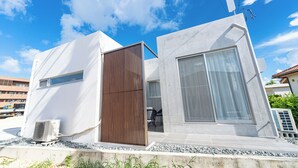 Een modern gebouw met een groot raam, een deur en een klein airconditioningsysteem op de begane grond.