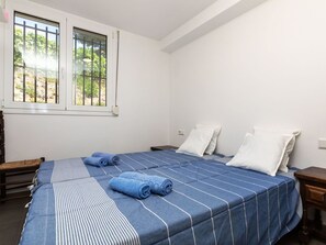 Quarto com duas camas, janela com grades e vista para o verde lá fora.