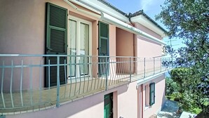 A two-story building with a balcony, a green door, and shutters on the windows. - Lovely apartment for 4 guests with WIFI, TV and balcony (Moneglia)