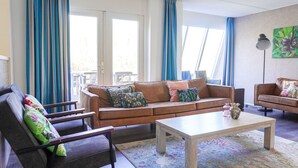 Un salon avec un canapé, un fauteuil, une table basse et un tableau accroché au mur.