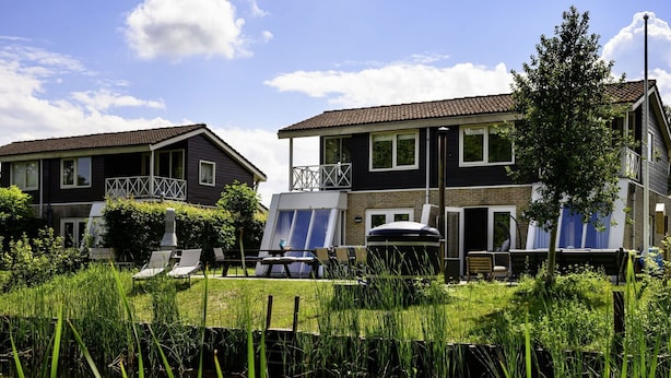 Un quartier résidentiel comprenant deux maisons, un étang et du mobilier d’extérieur.