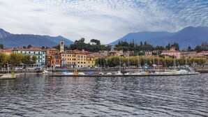 A waterfront town with colorful buildings, a clock tower, and boats docked along the river. - Nice apartment for 4 people with A/C, WIFI, TV and balcony (Porto Valtravaglia)