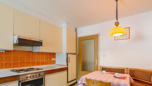 A compact kitchen with a gas stove, oven, and a dining area with a table and chairs.