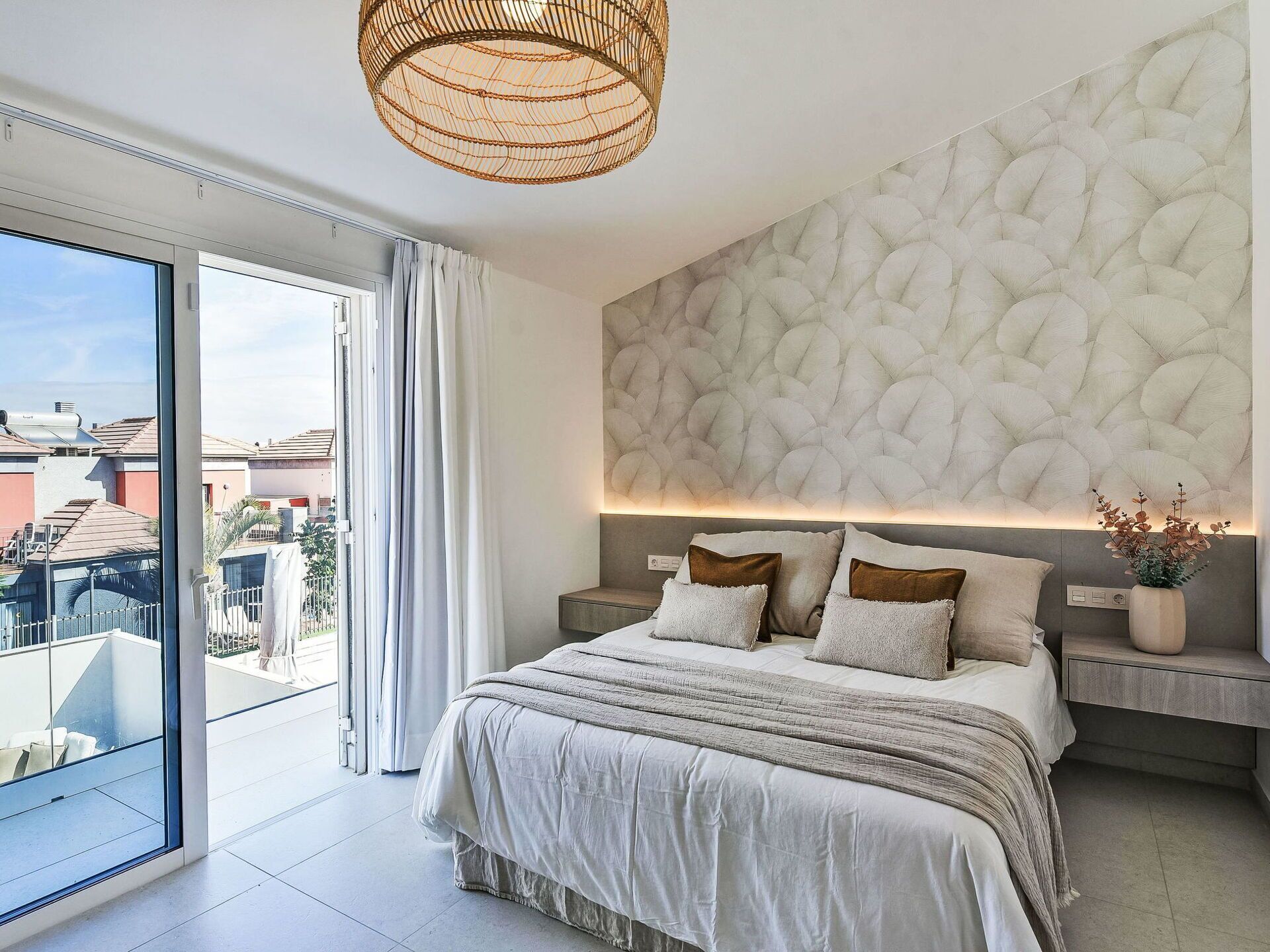 Une chambre moderne avec un grand lit, un mur décoratif et une vue sur la ville, visible à travers une porte coulissante.