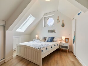 A bedroom with a sloped ceiling, a skylight, a bed with patterned bedding, bedside tables with lamps, and wall art. - Beautiful  villa for 4 guests with WIFI, TV, terrace and pets allowed (Saint-germain-sur-ay)