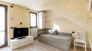 A room with a sofa, a TV, a chair, and a window with a view. - Nice apartment for 2 guests with WIFI, TV, balcony and pets allowed (Bormio)