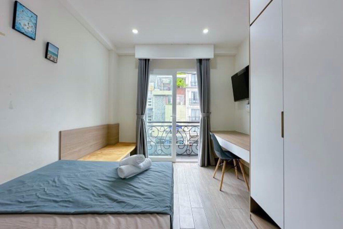 A bedroom with a bed, a desk, and a TV.