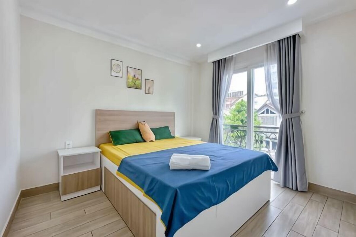 Ein Schlafzimmer mit Bett, Nachttisch und einem Fenster mit Vorhängen.