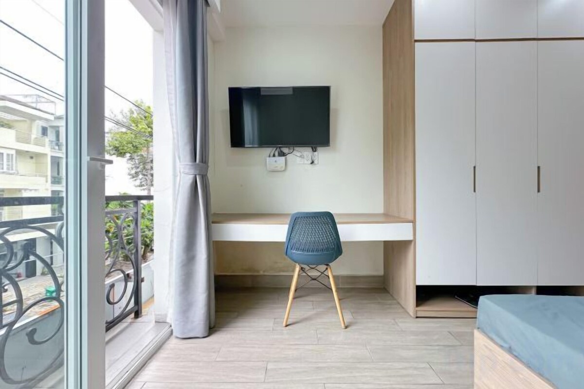 A room with a bed, a desk, a chair, a TV, and a wardrobe.