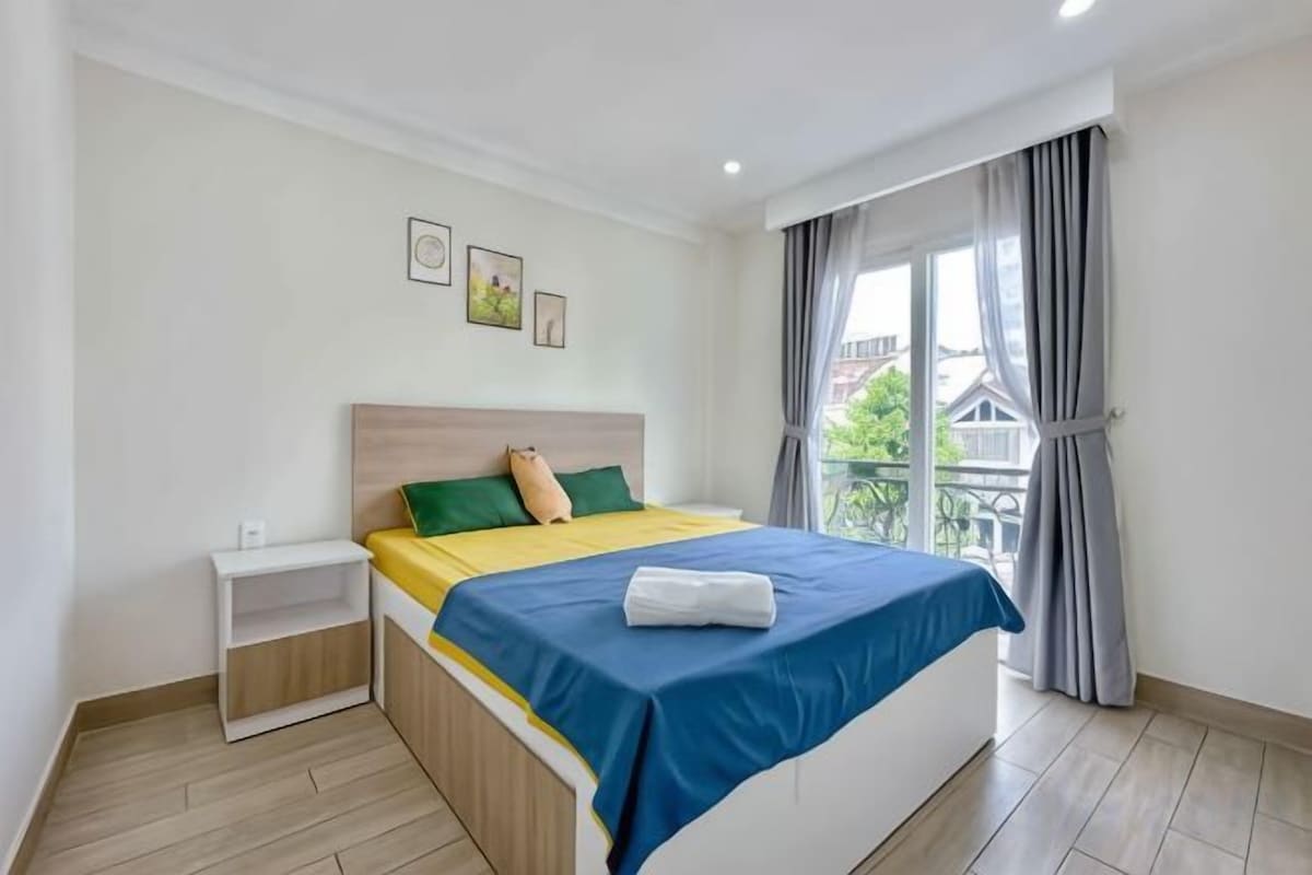 A bedroom with a bed, bedside table, and a window with curtains.
