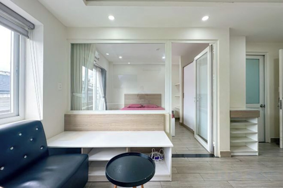 Quarto de hotel moderno com cama, área de estar e vista através de uma porta de vidro.