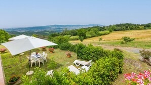 A patio with outdoor furniture, a table, and a large umbrella. - Beautiful apartment for 7 guests with pool, A/C, WIFI, TV, patio, pets allowed and panoramic view (Castellina Marittima)