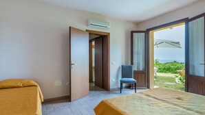 A hotel room with two beds, a chair, and a balcony with a view of greenery and mountains. - Beautiful apartment for 7 guests with pool, A/C, WIFI, TV, patio, pets allowed and panoramic view (Castellina Marittima)
