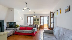 Amplia sala de estar con chimenea, una mesa de comedor y una cocina al fondo.