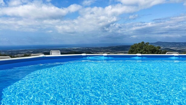 Piscina azul cristalina con vistas al paisaje y la ciudad al fondo.