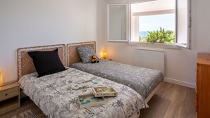 A bedroom with two beds, a window with a view, and a bedside table with a lamp. - Beautiful private villa for 6 guests with private pool, WIFI, TV and terrace (Préfailles)