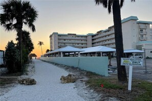 Un hotel frente a la playa con varias edificaciones, un paseo techado y un cartel que indica acceso privado a la playa para miembros e invitados.