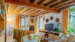 A cozy living room with a fireplace, wooden beams, a television, and a dining area with a table and chairs. - Stunning private villa with WIFI, private pool, TV, patio, pets allowed and panoramic view (Tione Di Trento)