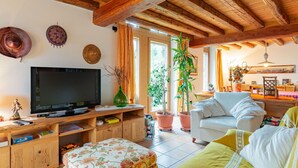 A cozy living room with a wooden ceiling, a television, a sofa, and a dining area with a table and chairs. - Stunning private villa with WIFI, private pool, TV, patio, pets allowed and panoramic view (Tione Di Trento)