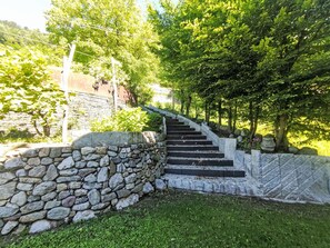 A stone staircase leading up to a building, surrounded by greenery and trees.