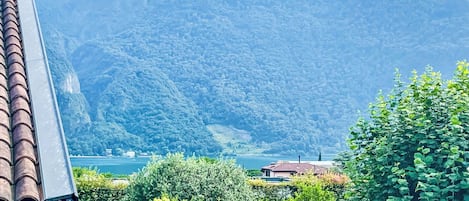 Un paysage montagneux avec un plan d’eau, un bâtiment doté d’un toit rouge et une végétation luxuriante.
