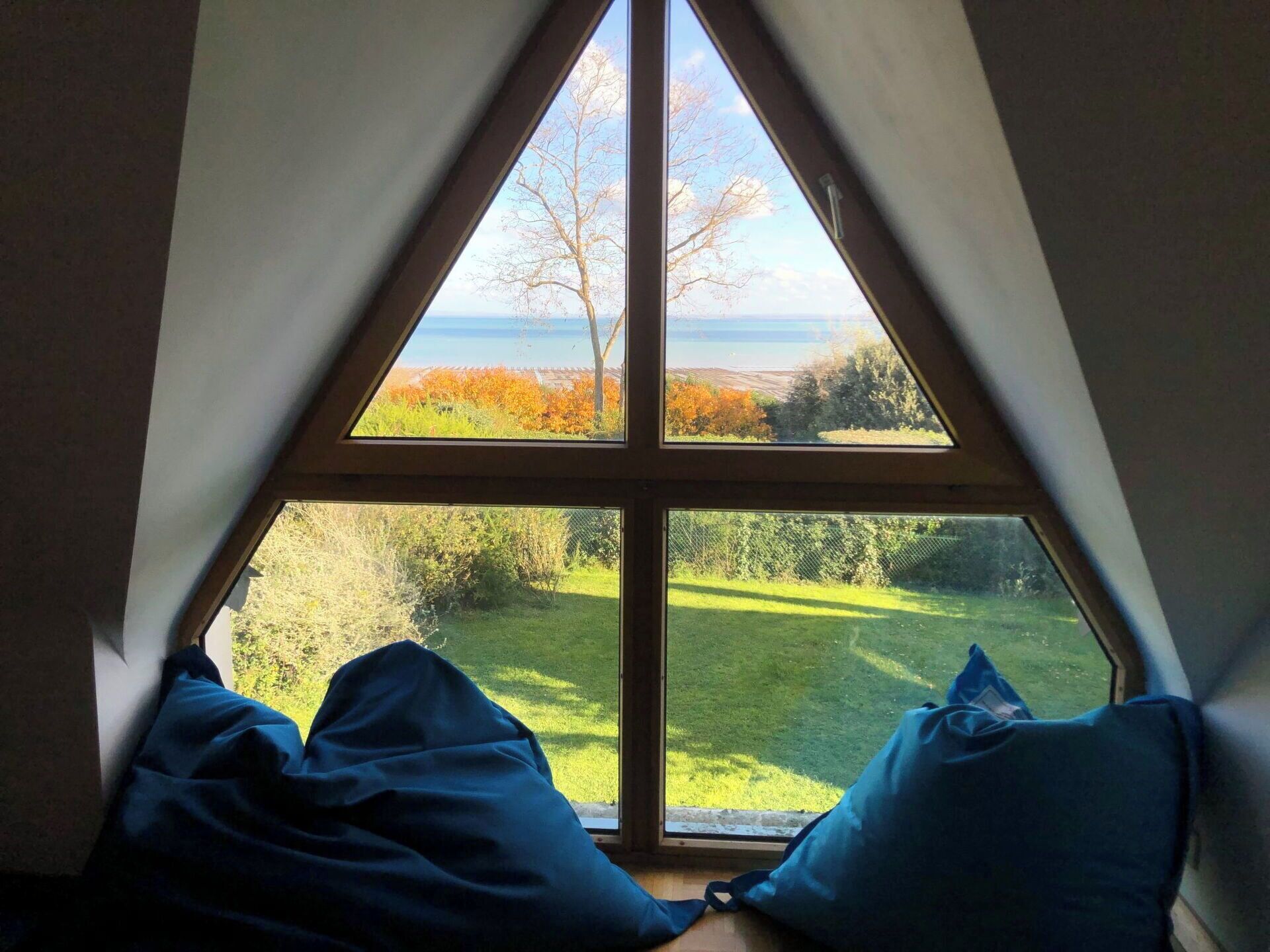 A room with a triangular window overlooking a grassy area and trees.