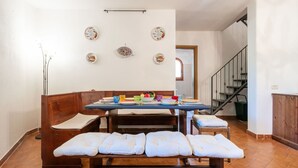 Un coin repas avec un banc en bois, une table dressée avec des assiettes et des verres, et des assiettes décoratives accrochées au mur.