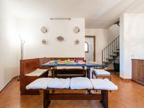 Een eethoek met een houten bank, een tafel gedekt met borden en glazen, en decoratieve borden aan de muur.
