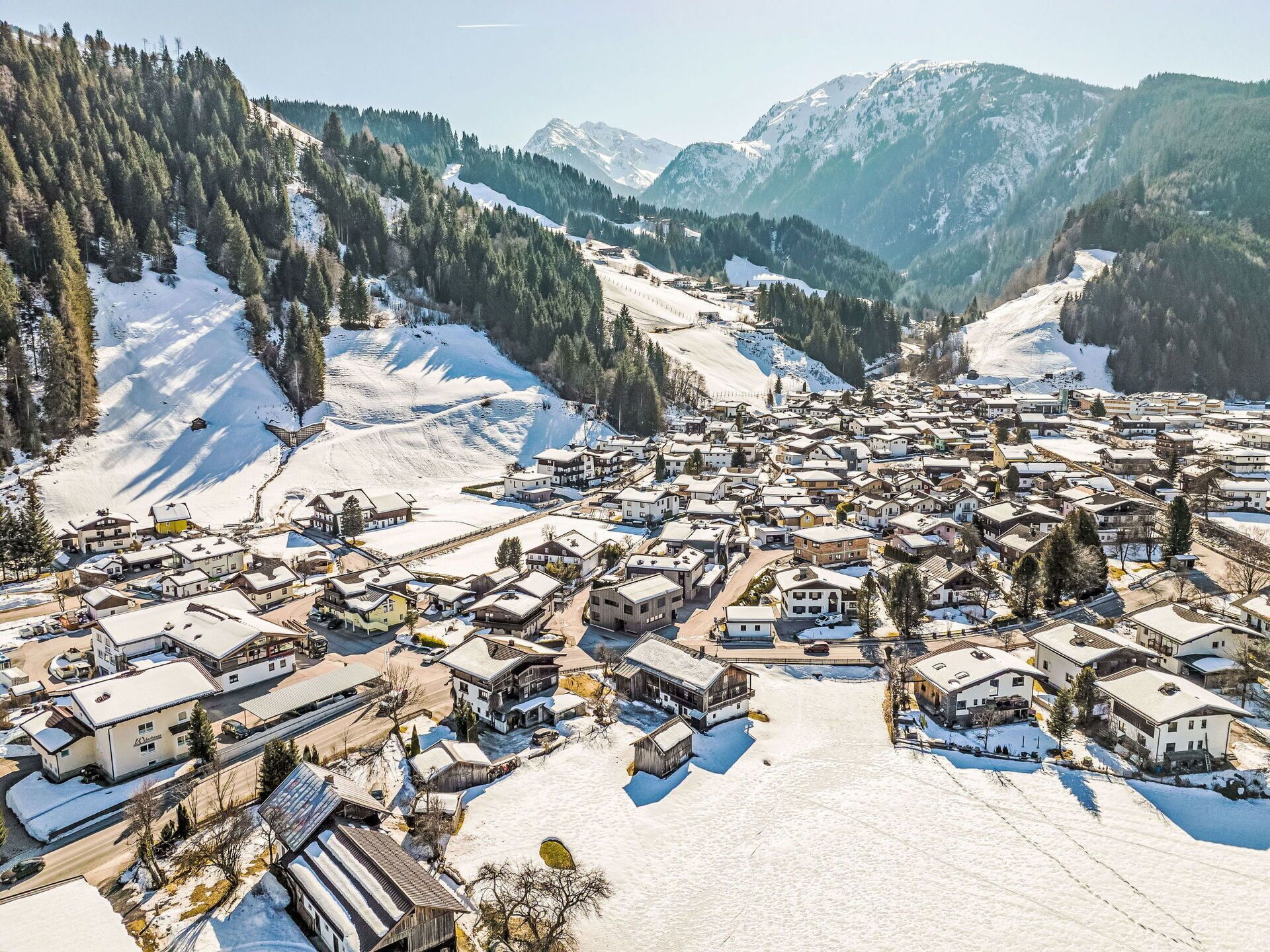 A snow-covered village with traditional buildings and a mountainous backdrop.