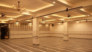 A spacious indoor area with a high ceiling, patterned walls, and a chandelier. - Hotel Midway Taj (Agra)