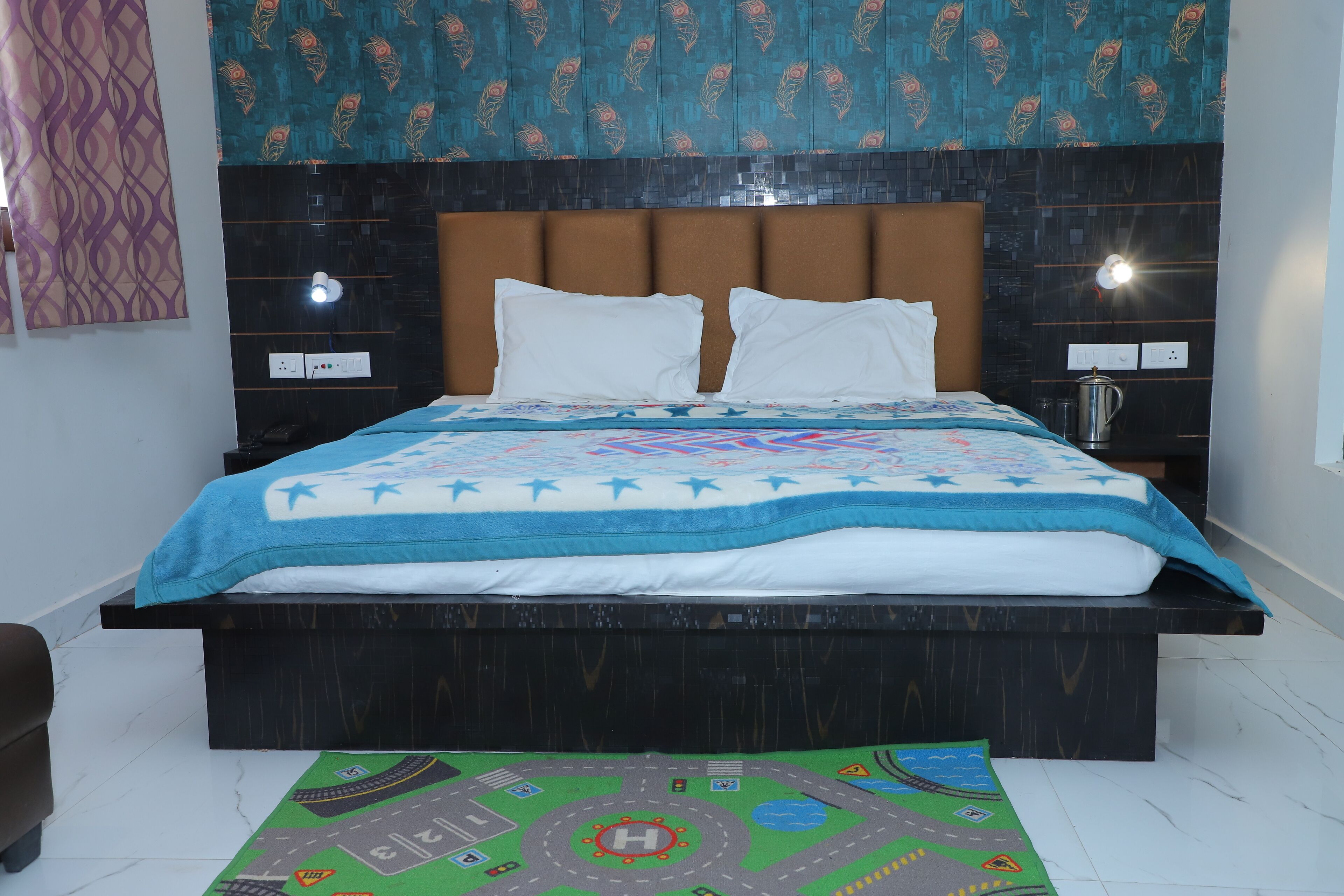 A neatly made bed with a blue and white patterned bedspread, a brown upholstered headboard, and two bedside lamps.