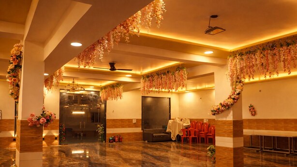 A spacious hall with a polished marble floor, a stage with chairs, and floral decorations. - Hotel Midway Taj (Agra)