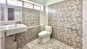 A bathroom with a mosaic tile wall, a white sink, and a toilet.