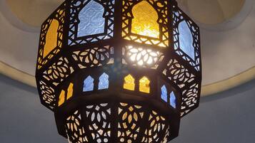A traditional lantern with intricate cut-out patterns, suspended from a ceiling with a floral design.