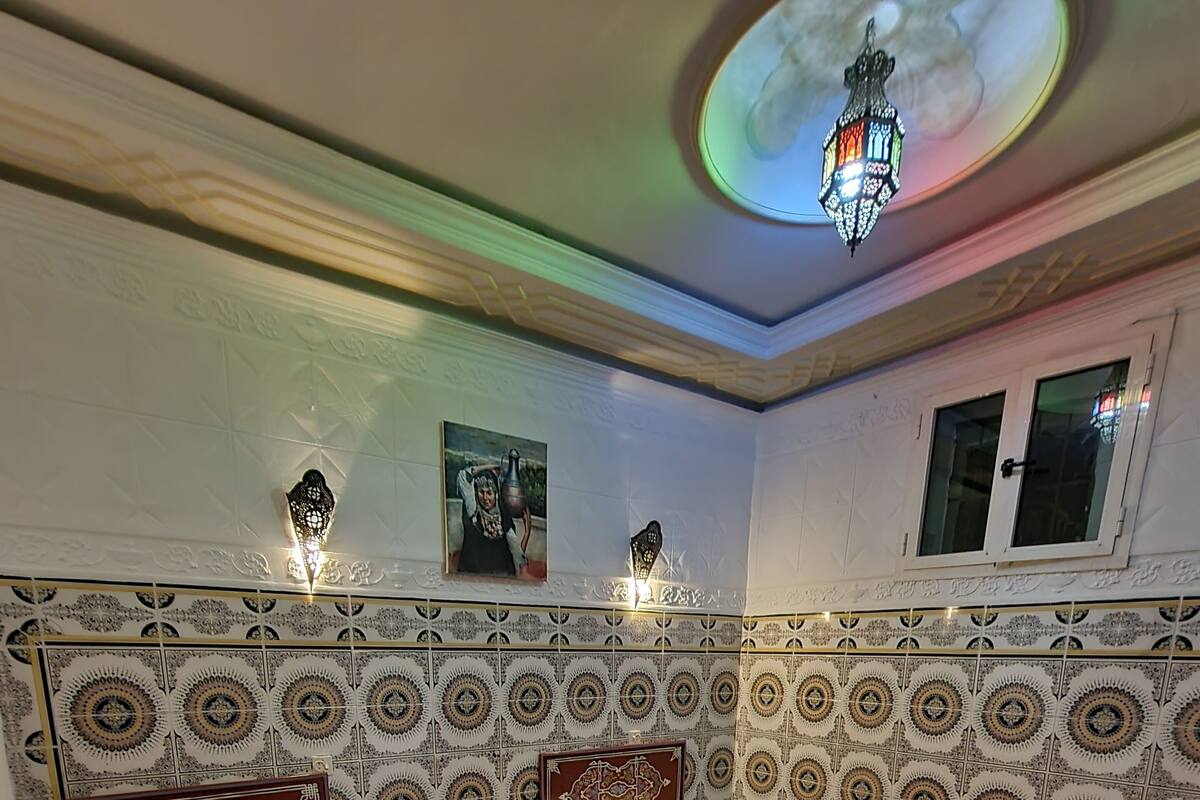 A traditional room with two beds, patterned walls, and a decorative ceiling light.