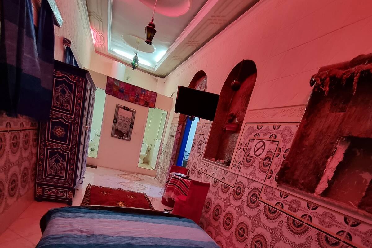 A room with a bed, a wardrobe, a mirror, and patterned walls.