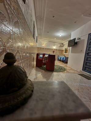 Eine Lobby mit aufwendigen Wandverzierungen, einem Empfangsbereich mit Fernseher und einem gemusterten Boden.