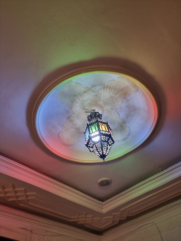 Un plafond orné d’un lustre décoratif et d’une lucarne circulaire.