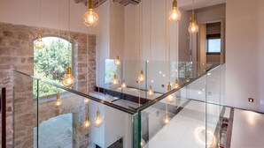 A modern interior with exposed brick walls, a glass staircase, and hanging pendant lights. - Beautiful private villa for 10 guests with private pool, WIFI, terrace and pets allowed (Roccastrada)