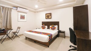 Une chambre d’hôtel équipée d’un lit, d’un bureau, d’une chaise et d’un appareil de climatisation.