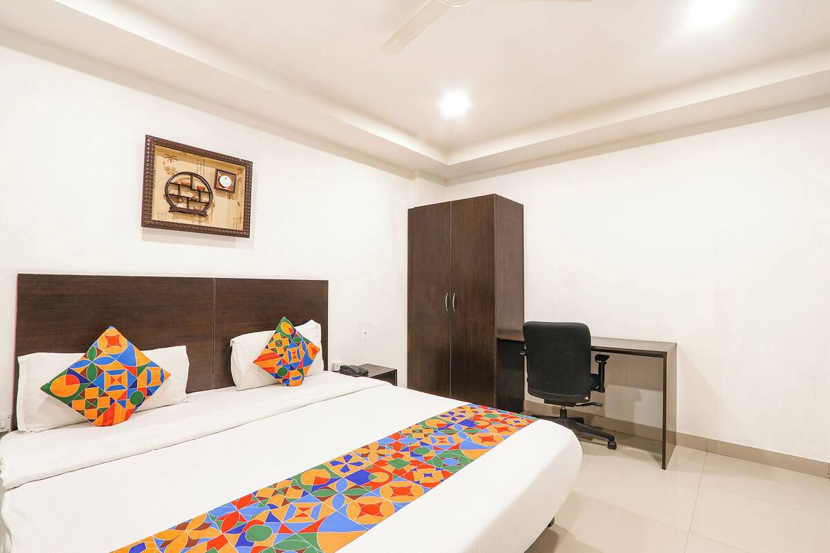 A hotel room with a large bed, a desk, and a wardrobe.