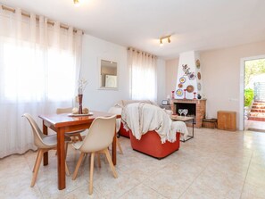 Ein Essbereich mit Holztisch und Stühlen, einer roten Couch und einem Kamin mit dekorativen Tellern.