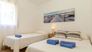 A room with two beds, a nightstand with a lamp, and a painting on the wall.