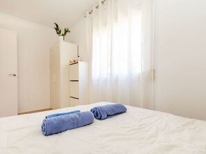 A hotel room with a bed, a wardrobe, and a window with sheer curtains.