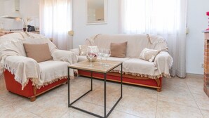 A living room with a red sofa, a beige sofa, a coffee table, and a fireplace.