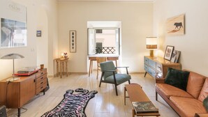 A living room with a sofa, a chair, a coffee table, a TV stand, and a rug. - Lovely apartment for 4 guests with A/C, WIFI (Rome)