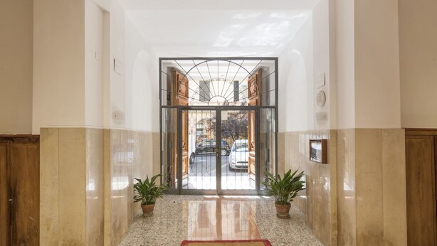 A hotel entrance with a polished marble floor, a red doormat, and two potted plants on either side. - Lovely apartment for 4 guests with A/C, WIFI (Rome)